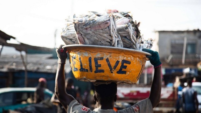 Image of a man carrying Slabs of frozen fish from Saiko making its way to the market.