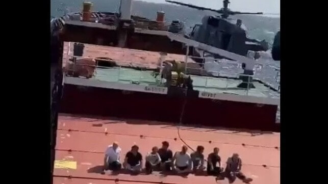 Crew of the Sukru Okan seated on deck as Russian boarding team departs