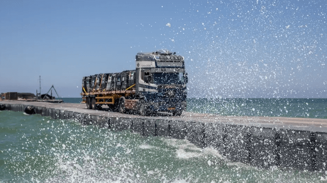 Aid truck crosses the floating causeway in mild swells, June 2024 (U.S. Army)