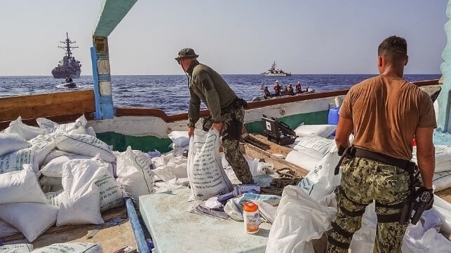 Sailors moving bags of explosives across the deck of a dhow 