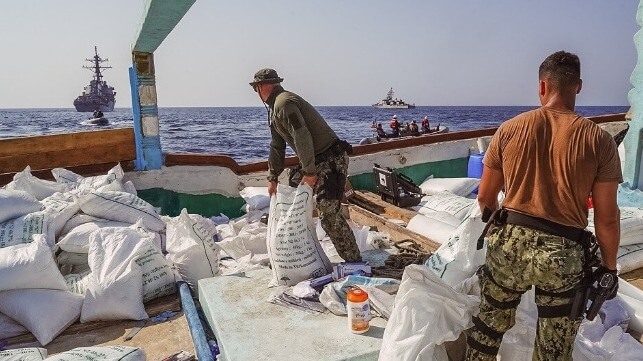 Sailors moving bags of explosives across the deck of a dhow