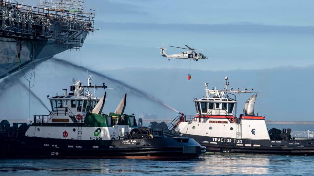Tugs provide cooling water on the bow as firefighting efforts continue, July 15 (USN)