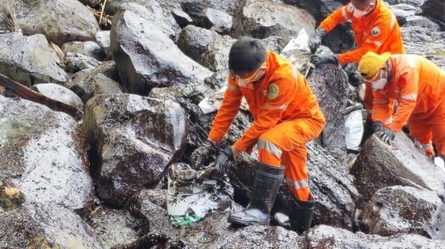 Philippine Coast Guard personnel and cadets from the Philippines' Norwegian Training Center clean oil off the rocks at the town of Pola (PCG)