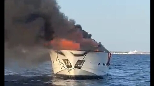 The burning remains of the Irmao towed away from a busy anchorage off Formentera (Salvamento Maritimo)
